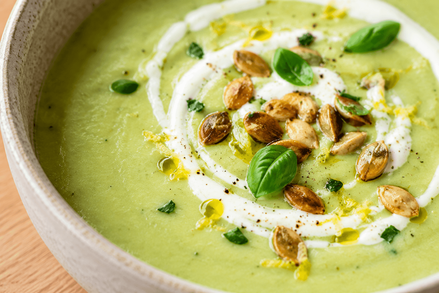 Close-up van gladde courgettesoep met crème fraîche en basilicum