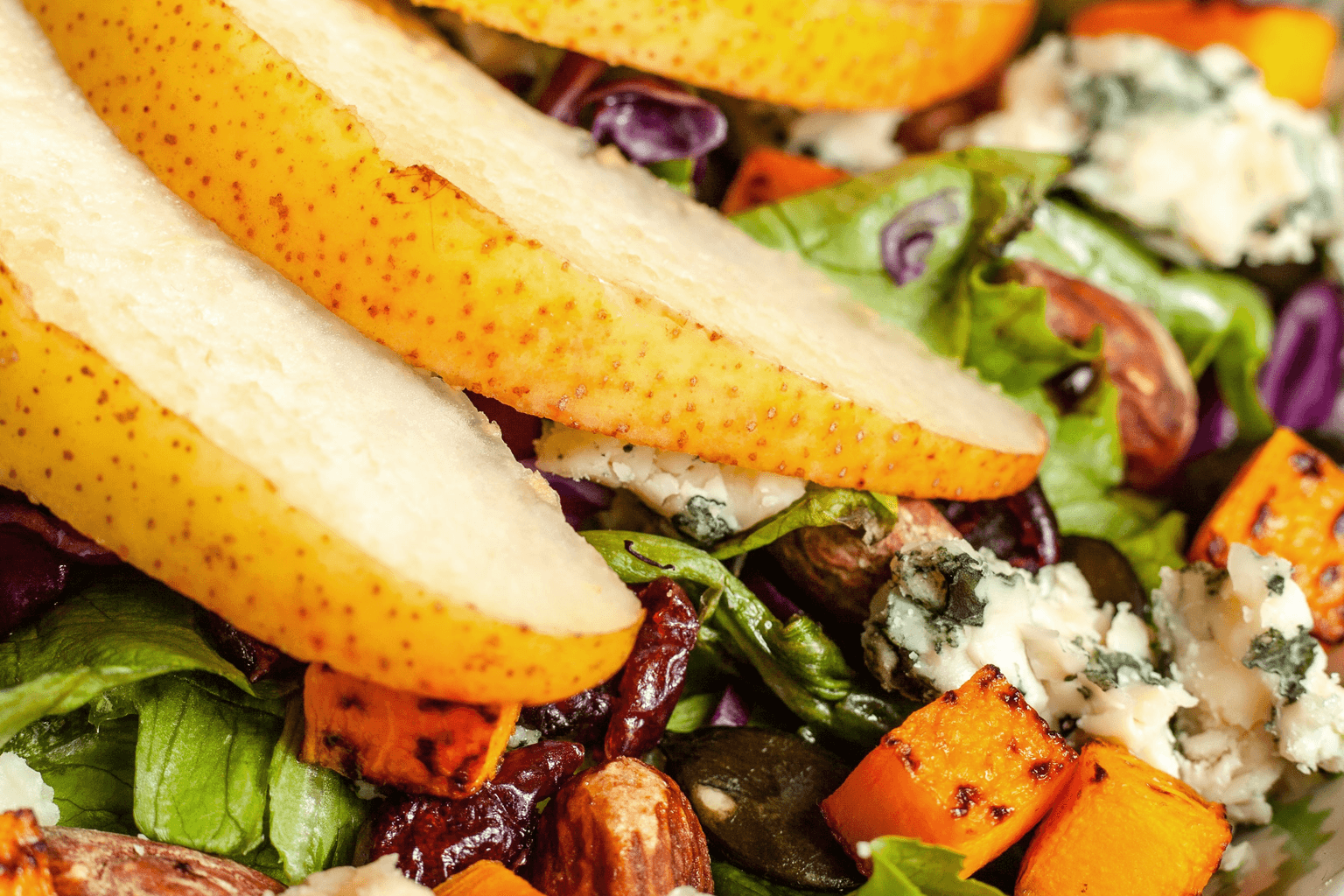 Close-up van salade met peer, geitenkaas en walnoten